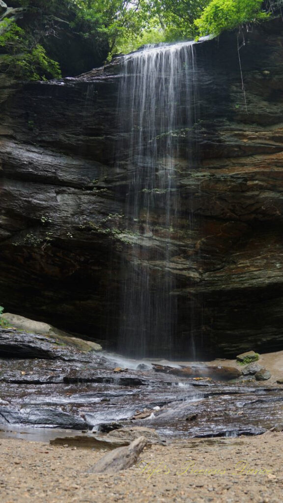 Moore cove Falls spilling over a jagged rockface into a mountain stream below.