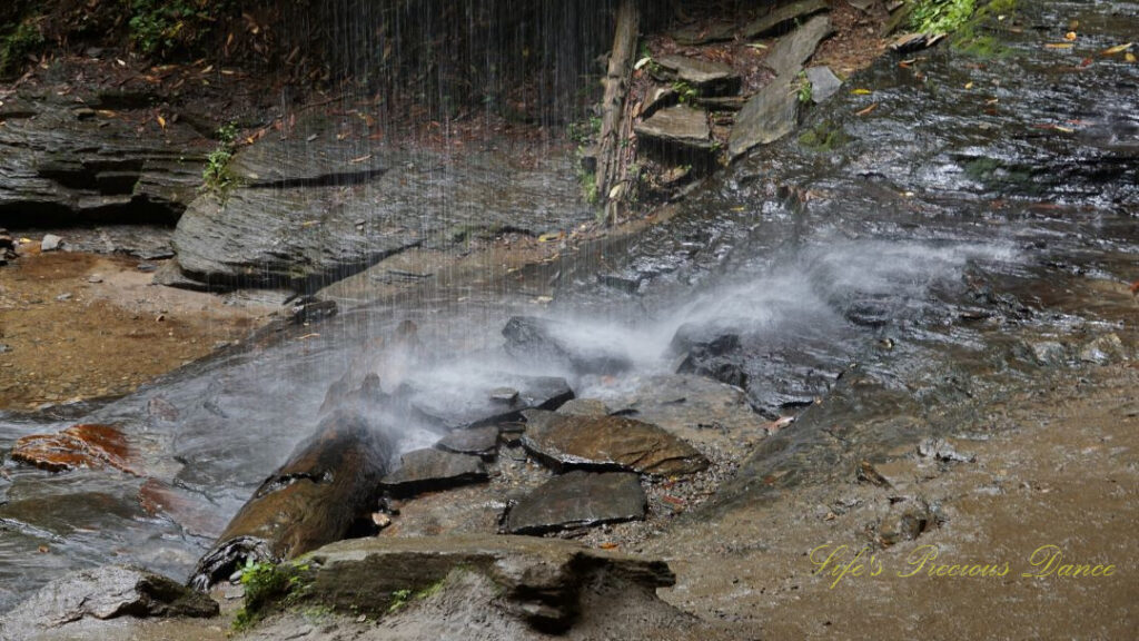 Close up of base of Moore Cove Falls cascading off of the rocks into a mountain stream.