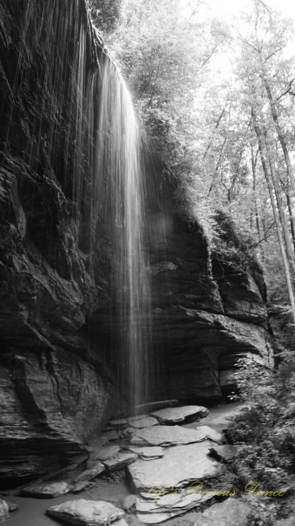 Black and white of Moore Cove Falls spilling over the rock ledge into a pool of water below.