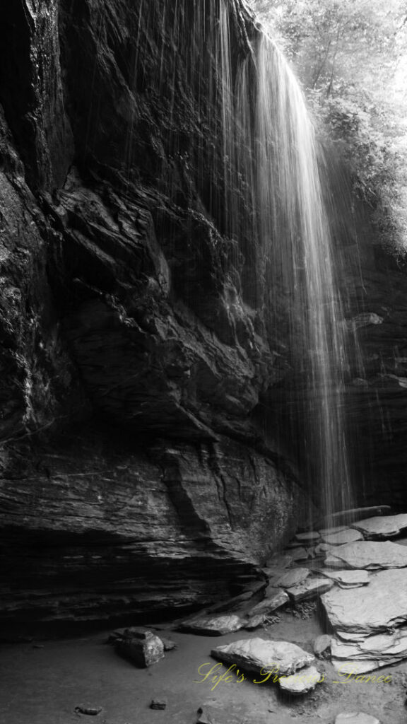 Black and white of Moore Cove Falls spilling over the rock ledge into a pool of water below.