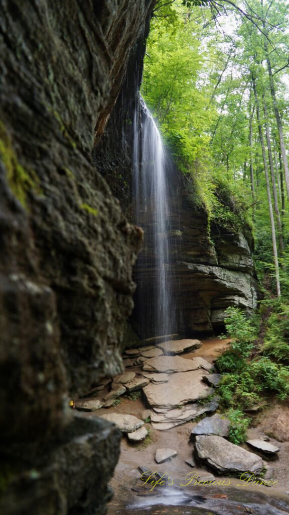 Side view of Moore Cove Falls spilling over the rock ledge into a mountain stream below.