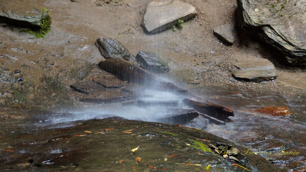 Close up of base of Moore Cove Falls cascading off of the rocks into a mountain stream.