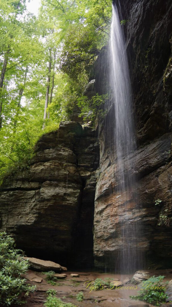 Side view of Moore Cove Falls spilling over the rock ledge into a pool of water below.