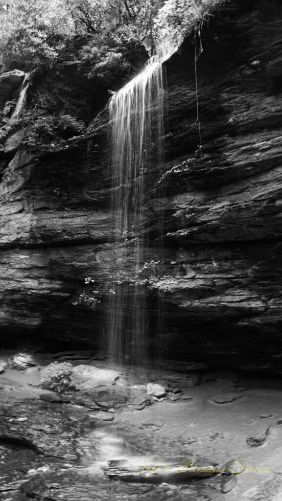 Black and white of Moore Cove Falls spilling over the rock ledge into a pool of water below.