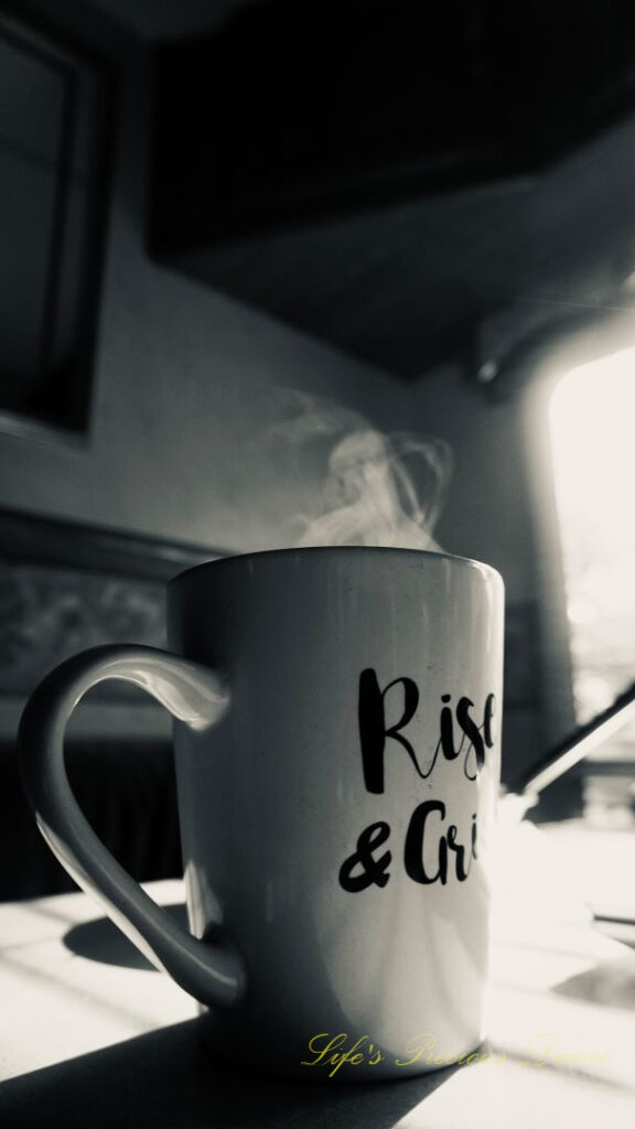 Black and white of a coffee mug on a table with steam rising from the top.