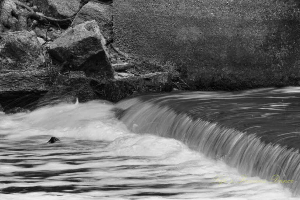 Black and white close up of rushing water spilling over a small ledge at Juniper Creek