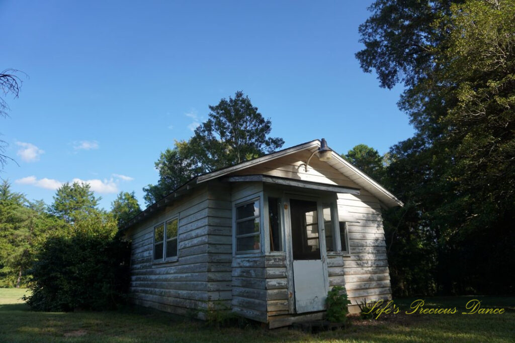 A small old pottery house surrounded by trees.