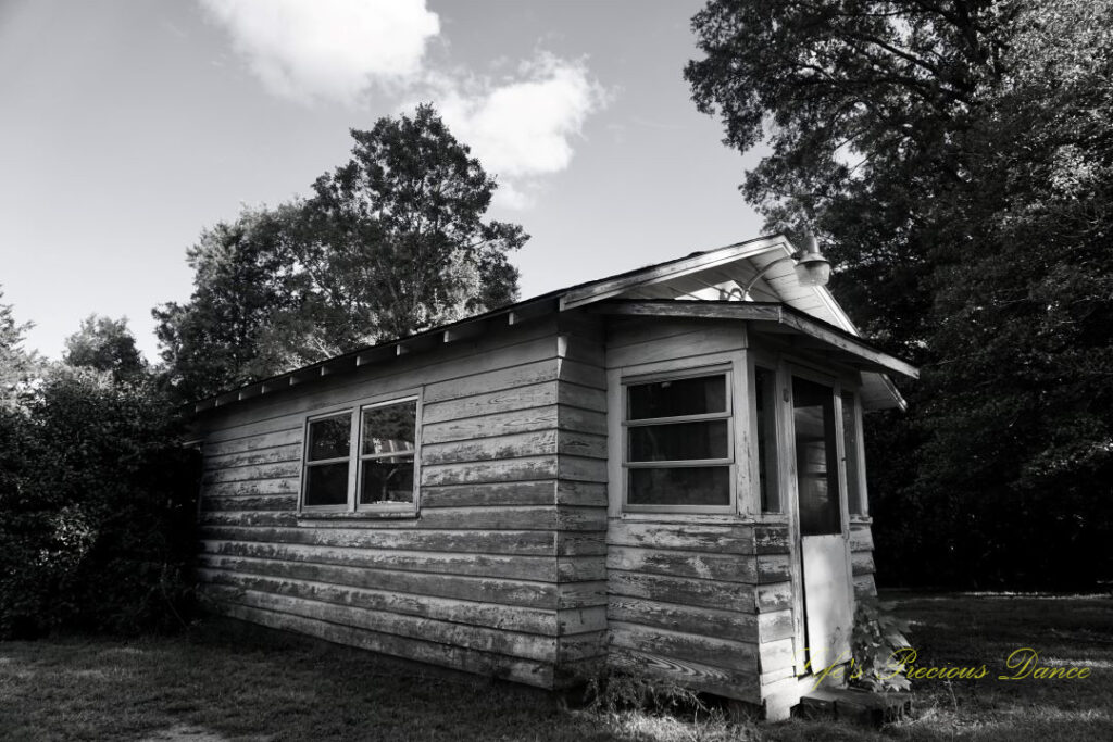 Black and white of a small pottery house. A few passing clouds overhead.