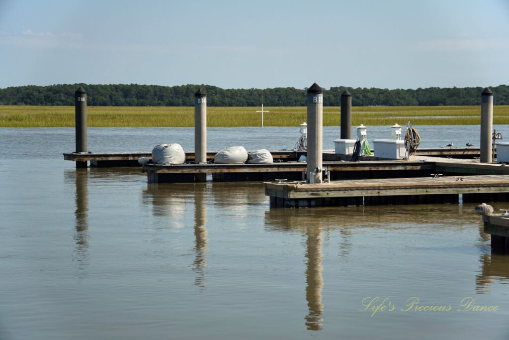 Several docks lined up along a pier at Edisto Island. A cross can be seen in the background.