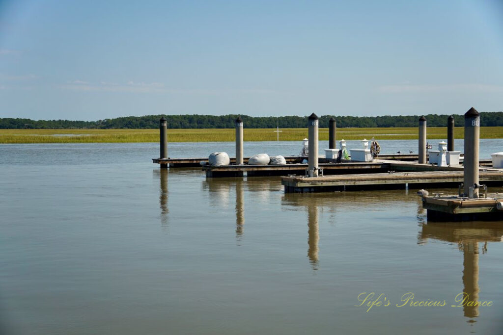 Several docks lined up along a pier at Edisto Island. A cross can be seen in the background.