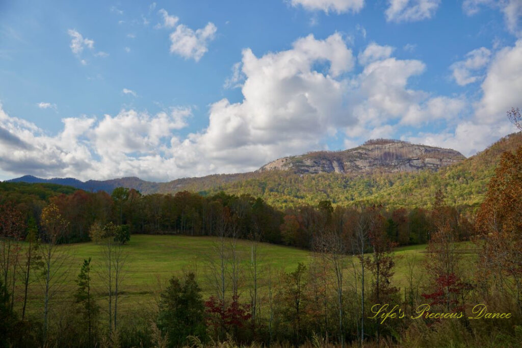 Landscape view of Table Rock and the surrounding mountain range from Grant Meadow Overlook. Passing fluffy clouds overhead.