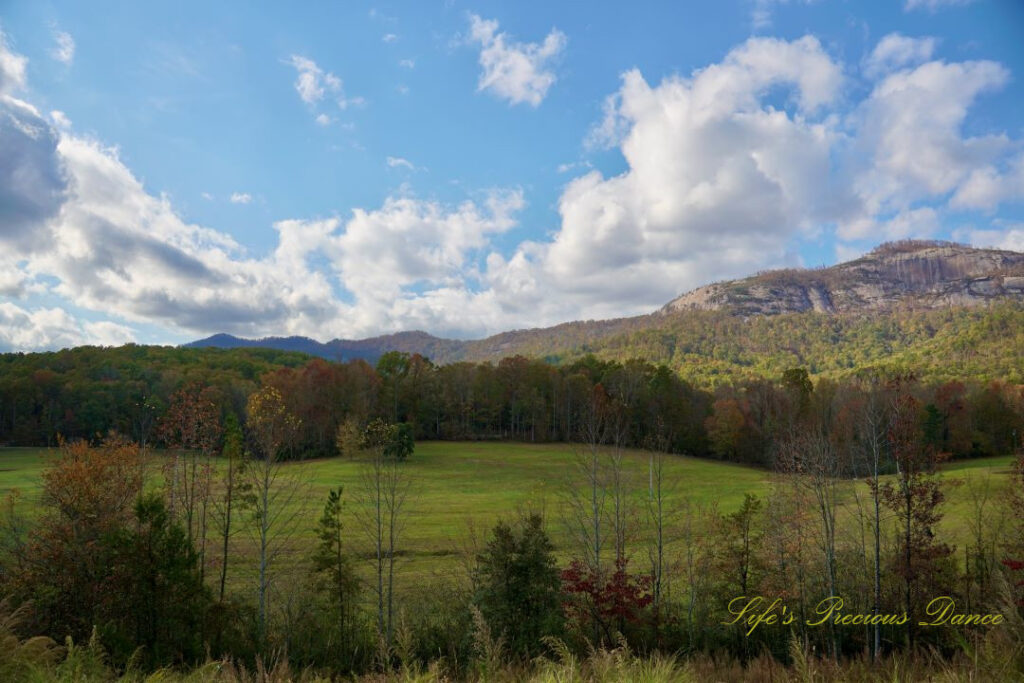 Landscape view of Table Rock and the surrounding mountain range from Grant Meadow Overlook. Passing fluffy clouds overhead.