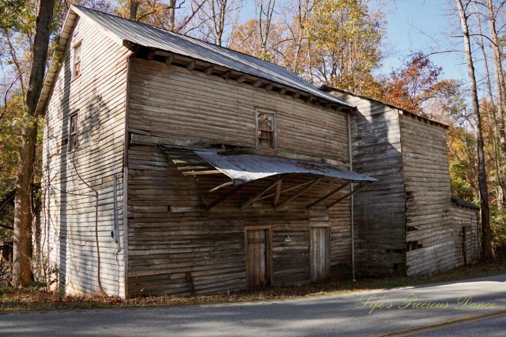 Front and side view of Historic Gilreath&#039;s Mill. Colorful trees in the background.