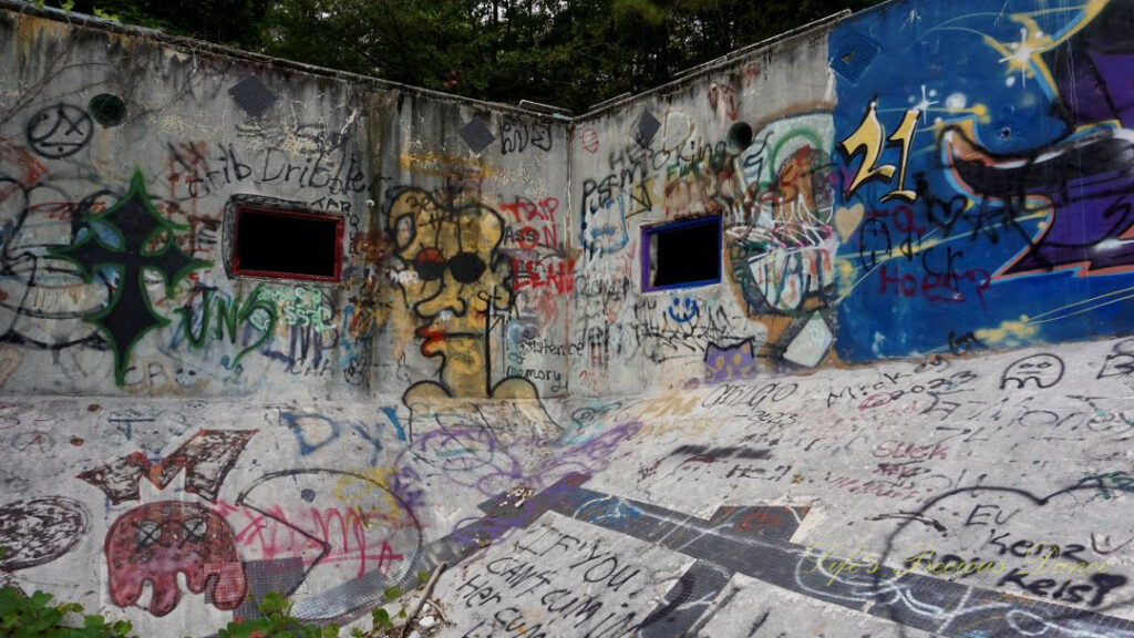 View from the deep end, looking upward at the graffiti covered corner of Springs Recreation Pool. Two windows in the walls.