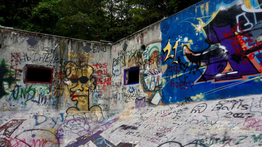 View from the deep end, looking upward at the graffiti covered corner of Springs Recreation Pool. Two windows in the walls.