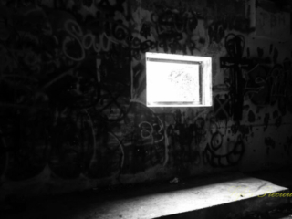 Black and white view of a window on a graffiti covered wall in the abandoned pump room at Springs pool.