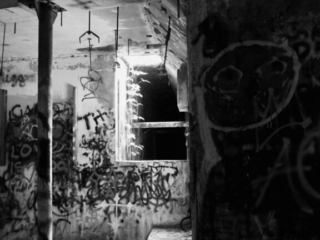 Black and white view of the graffiti covered pump room, located below the water level at abandoned Springs pool.