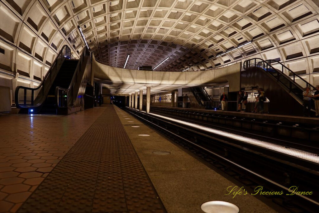 Looking down the tracks of the DC Metro Subway Train station. Escalators on either side.