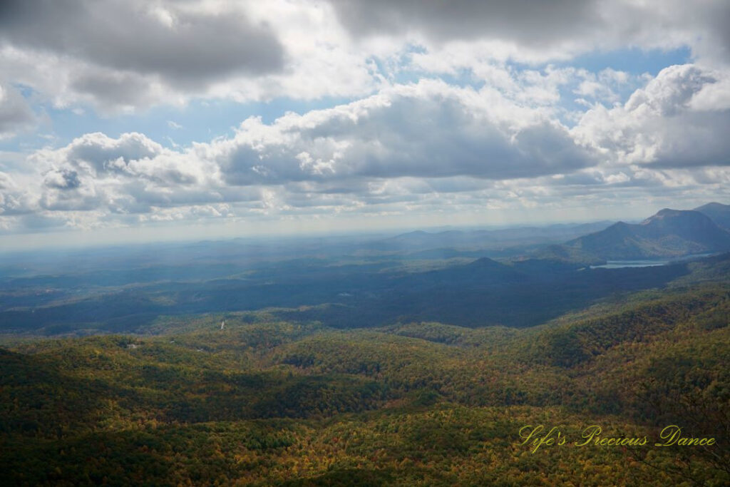 Landscape view from Caesars Head overlook. The suns rays cascade through overhead passing clouds and a lake can be seen in between the mountain ranges.