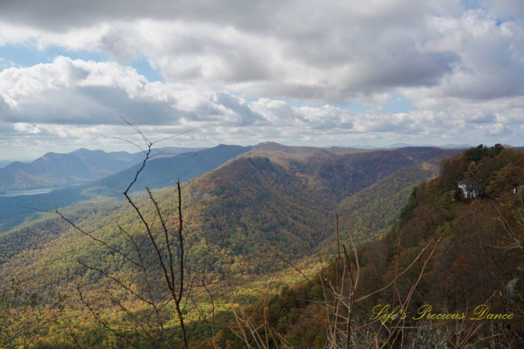 Landscape view from Caesars Head Overlook. A lake can be seen in the distance and a house is tucked away in the mountains to the right