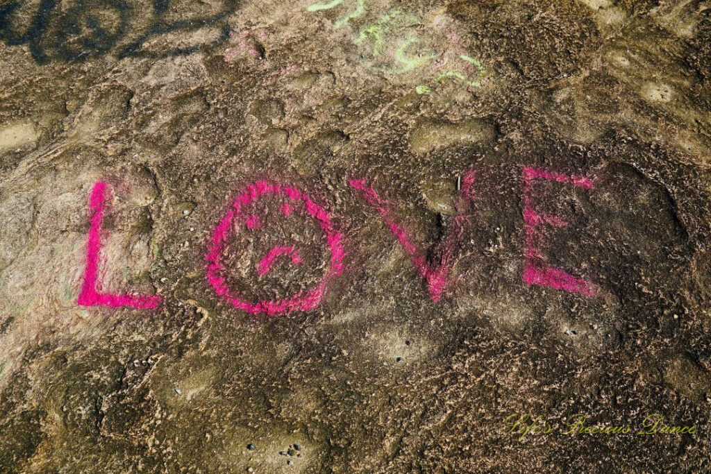 The word &quot;Love&quot;, in bright pink, spray painted on the face of Bald Rock.