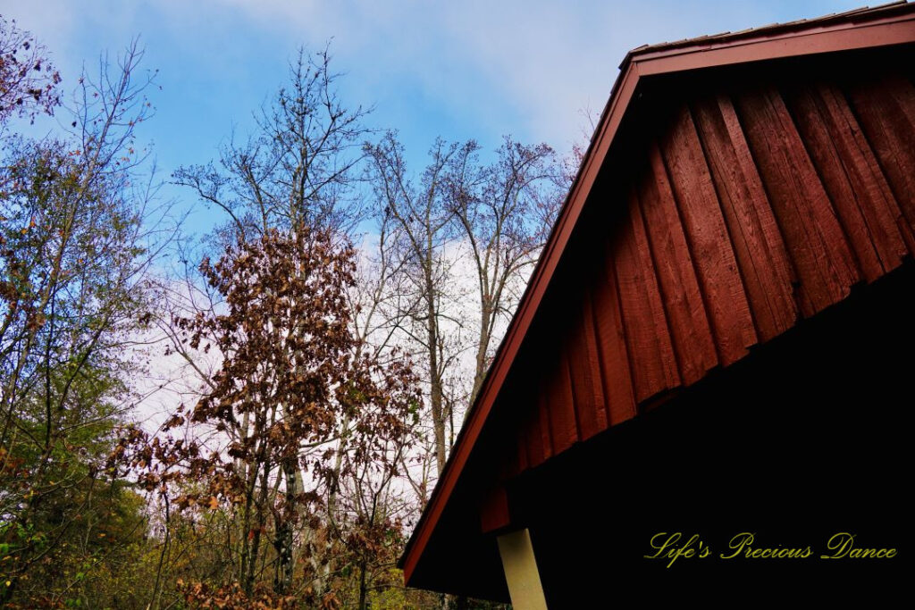 Looking upward at the roof and entrance of Campbell&#039;s Covered Bridge. Trees to the left and passing clouds overhead.