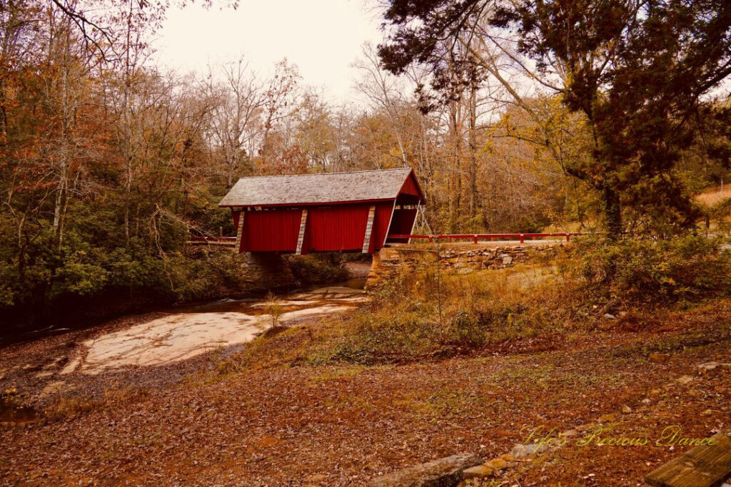 Distant view of Campbell&#039;s Covered Bridge spanning the creek. Surrounded by colorful trees.