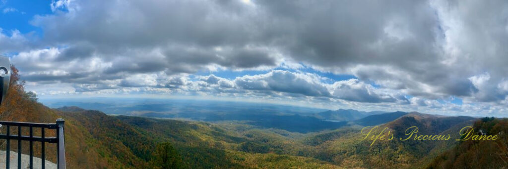 Panoramic landscape view of colorful mountain peaks and the valley from Caesars Head overlook. Passing clouds overhead.