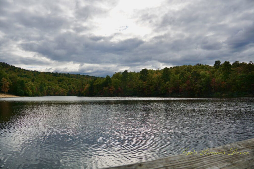 Waterscape view of Hanging Rock Lake. Colorful trees in the background and cloudy skies overhead.