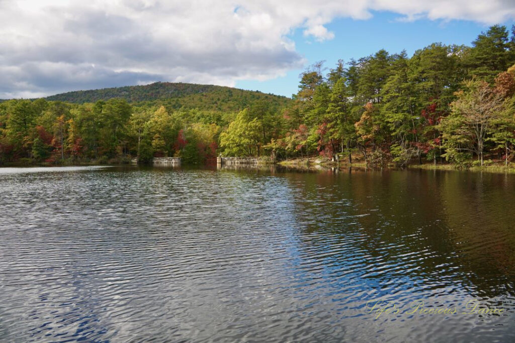 Waterscape view of Hanging Rock Lake. Trees and a mountain range in the background. Passing clouds overhead.