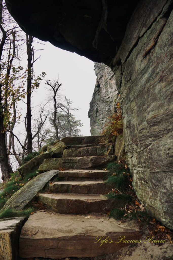 Stone steps running beside the base of Pilot Mountain. Fog and trees in the background.