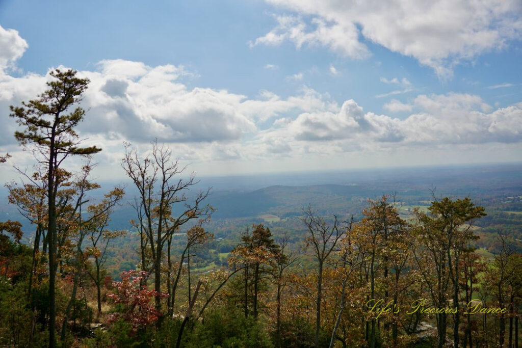 Landscape view of a valley below Pilot Mountain. Fluffy clouds against a Carolina blue skies above.