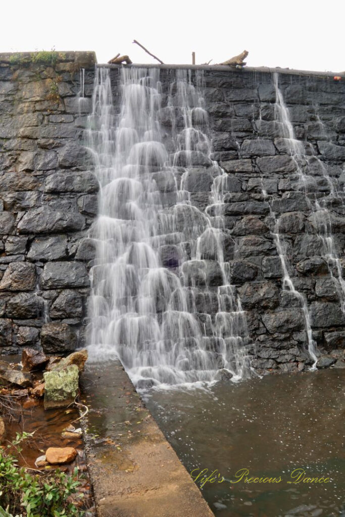 Waterfall spilling down a rockwall into an awaiting creek below.